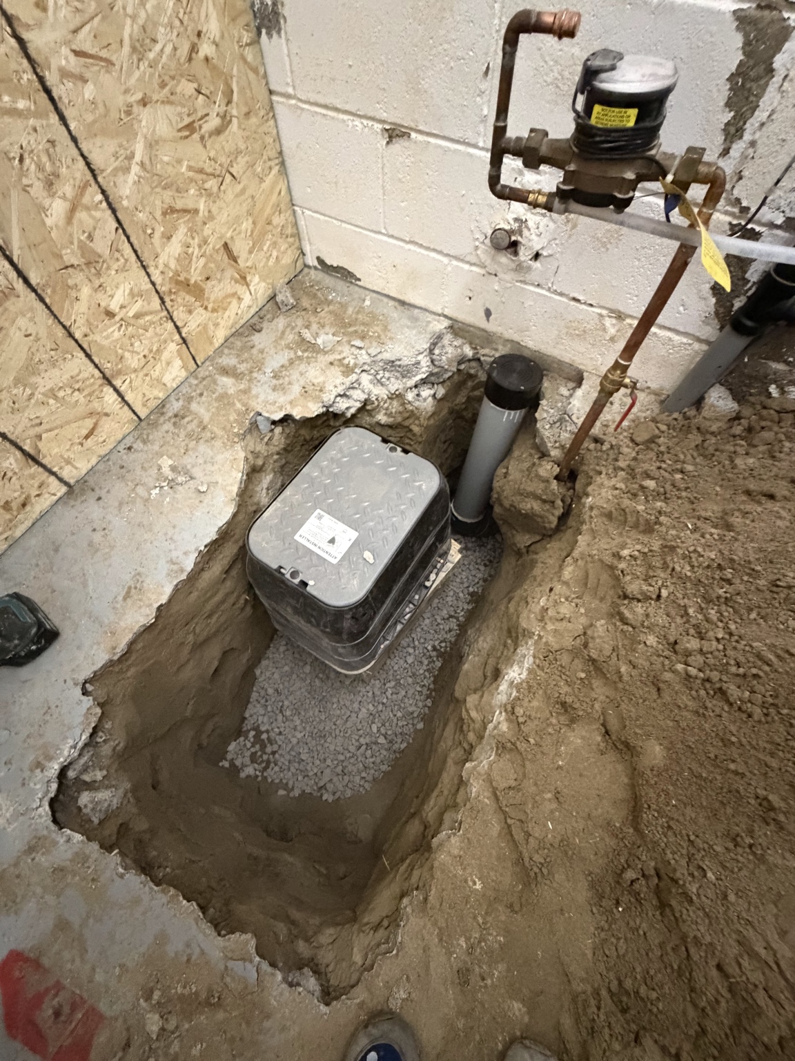 Backwater valve installed in excavated basement floor with drainage piping
