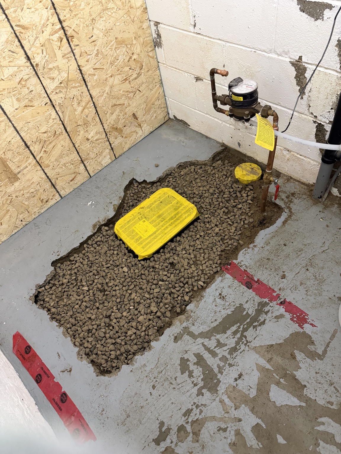 Backwater valve installation backfilled with gravel before concrete restoration