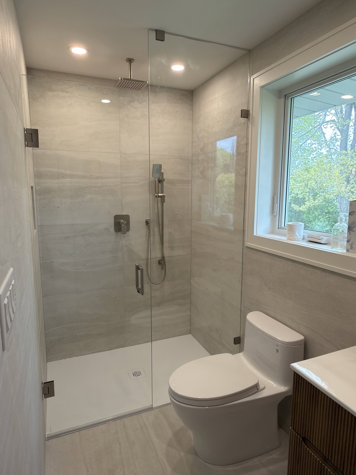 Glass shower with large-format tile and modern toilet