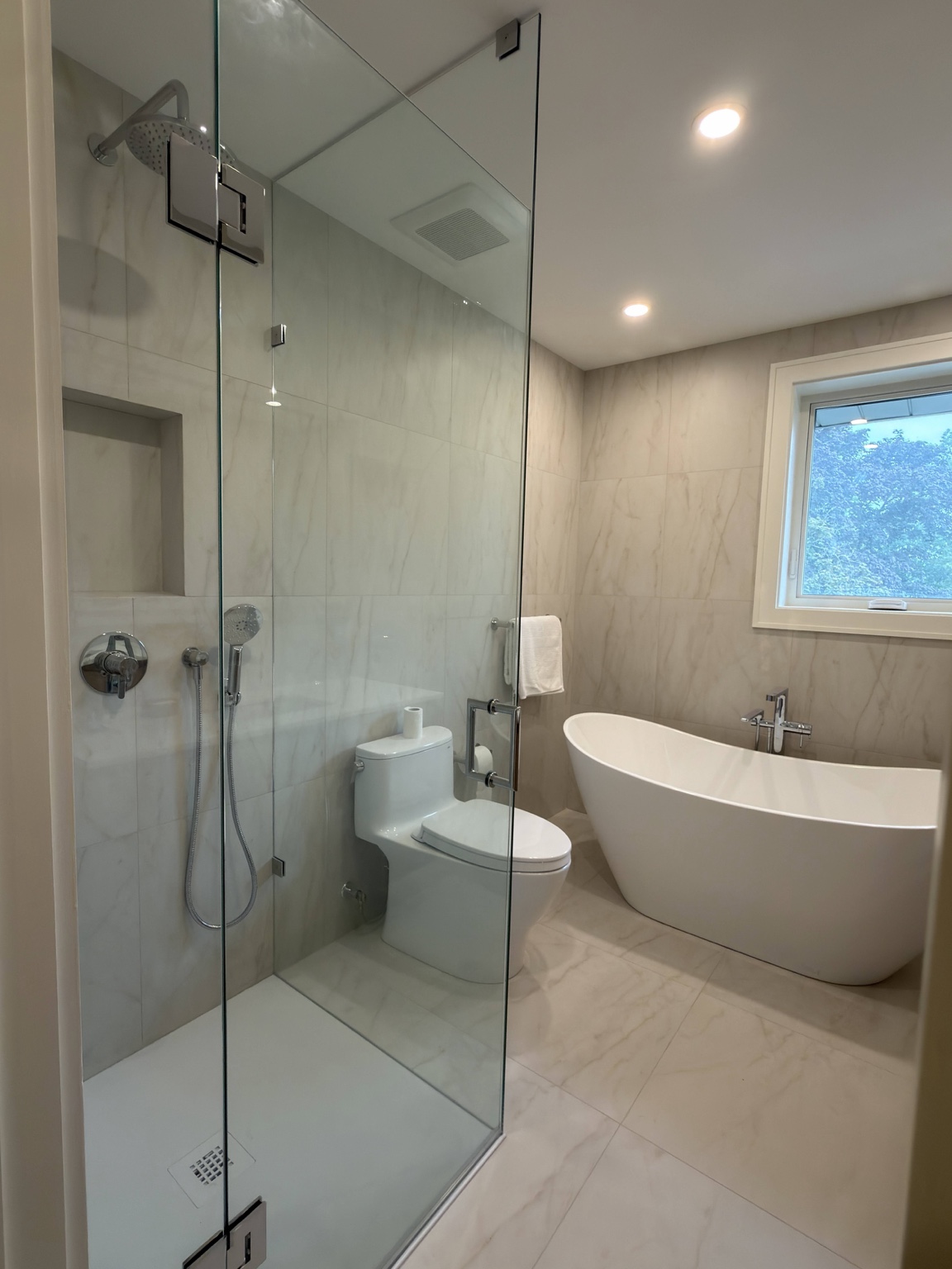 Bathroom renovation with glass shower, toilet and freestanding bathtub