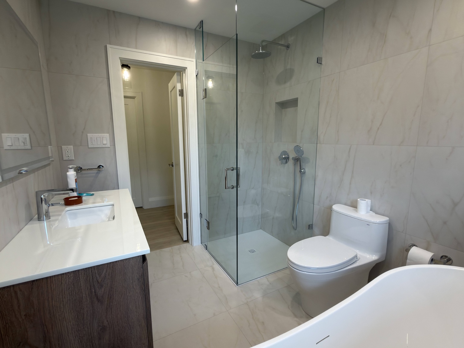 Completed bathroom renovation with vanity, glass shower and bathtub